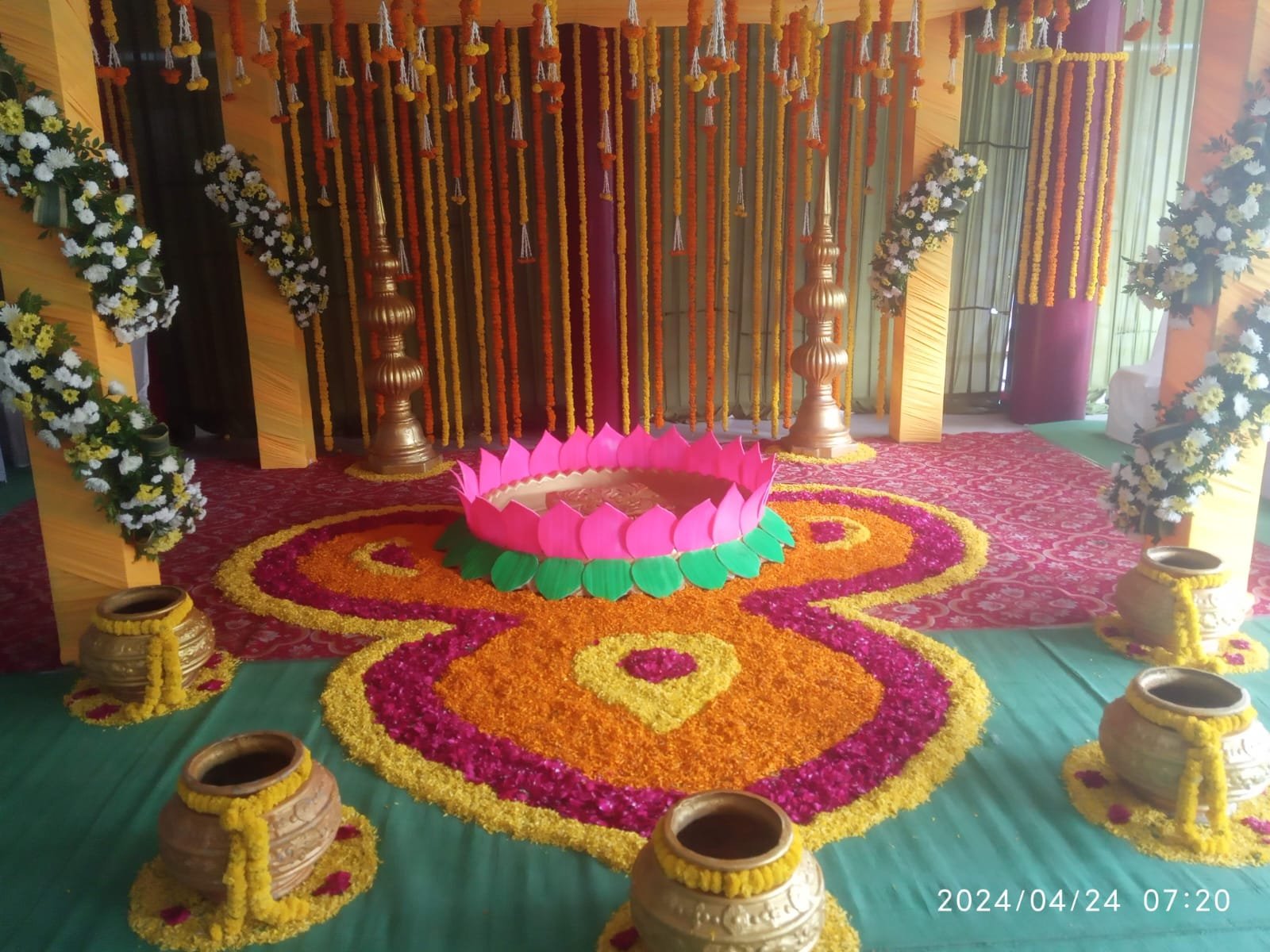 Large indoor family function setup with rangoli and drapes